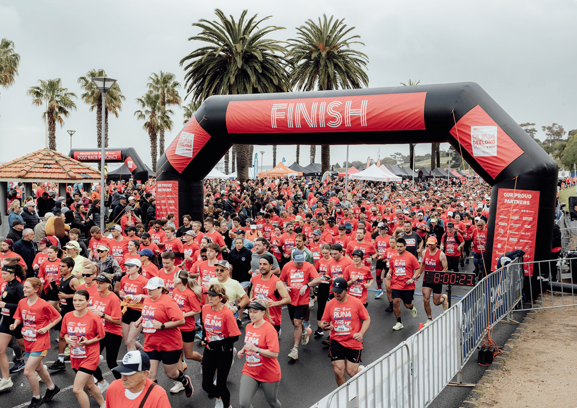 Thousands of runners in red Run4Geelong shirts crossing the start line on the Geelong waterfront